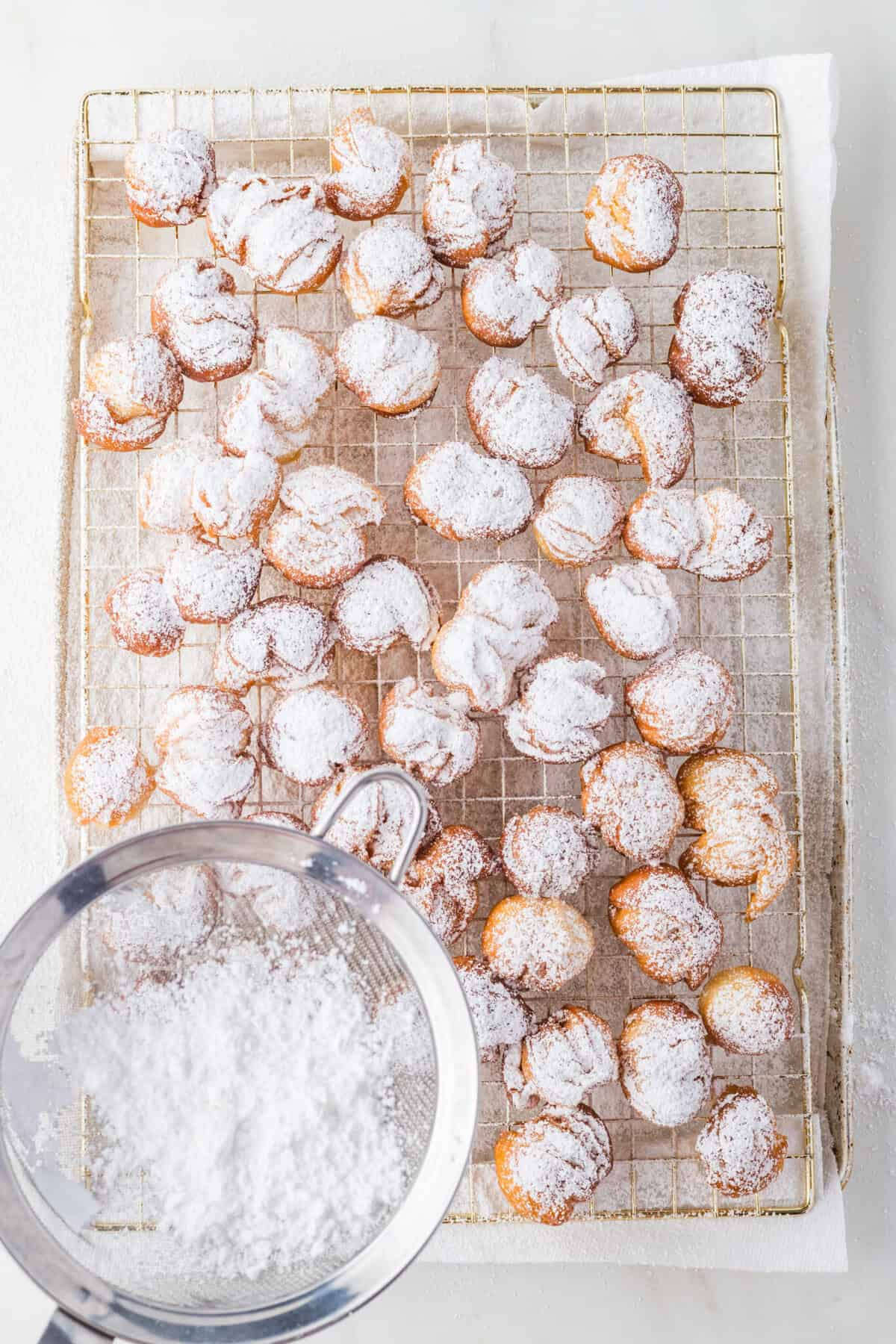 dusting donut holes with powdered sugar