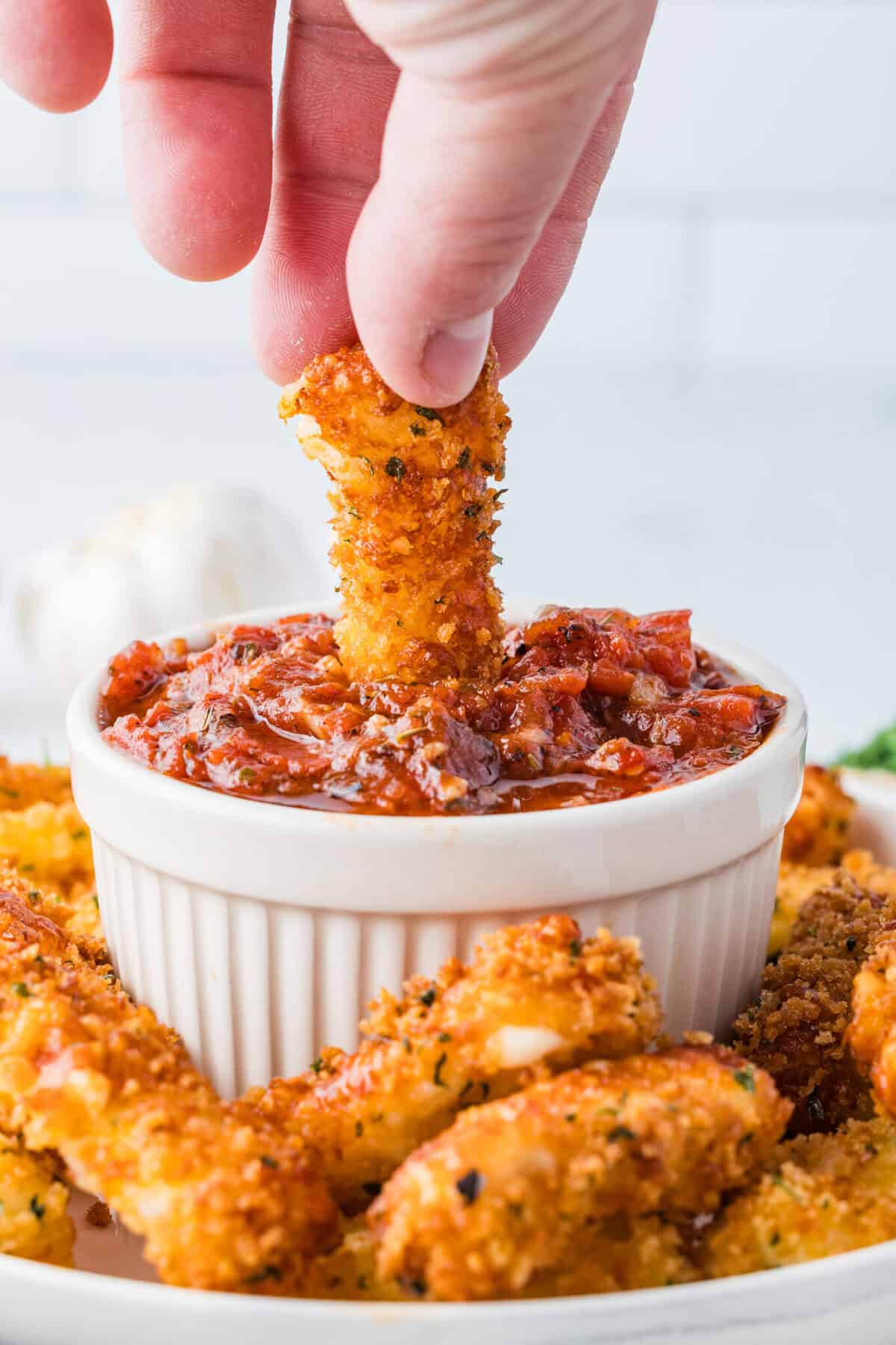 dipping a mozzarella stick in marinara sauce