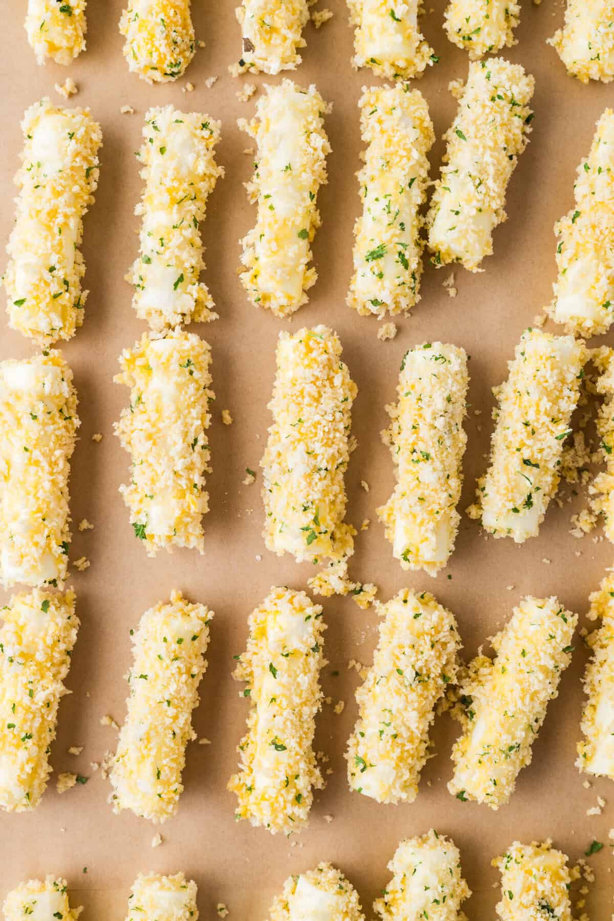 panko coated cheesesticks on a baking sheet with parchment paper lining