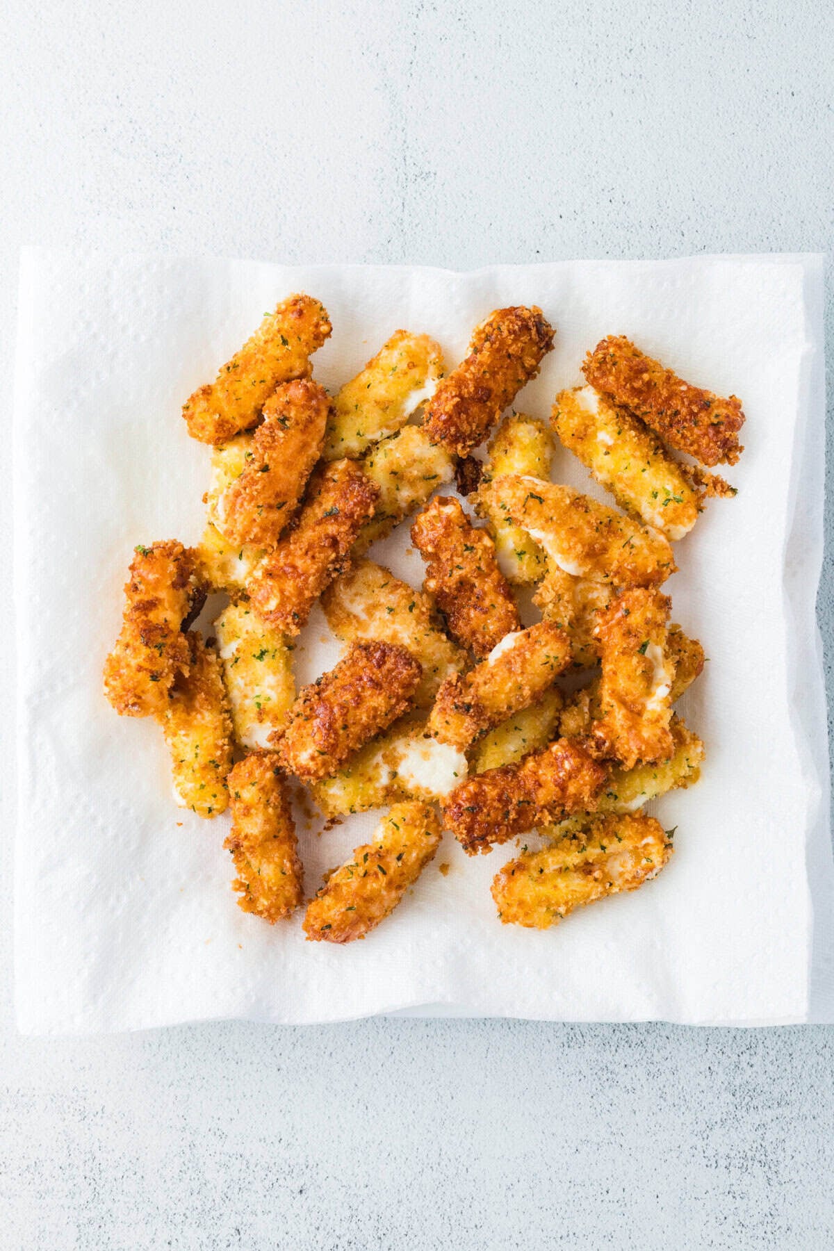fried mozzarella cheesesticks draining on paper towels