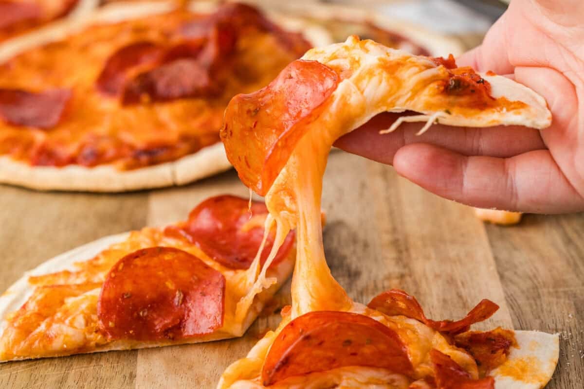 sliced air fryer pizza with melted cheese pulling away