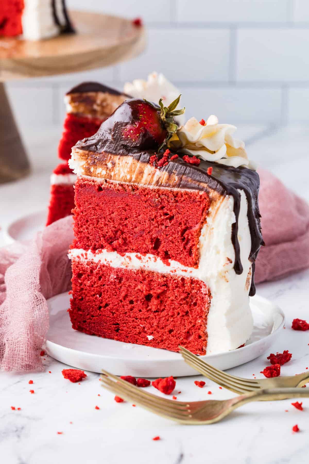 slice of red velvet cake with strawberries and ganache