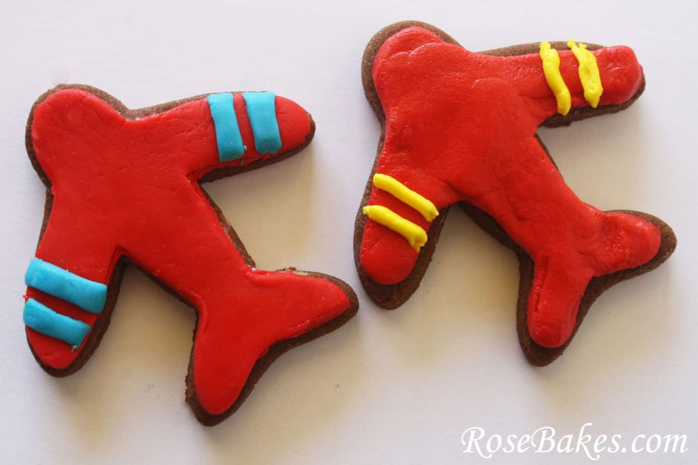 two Cookies that are shaped like airplanes and frosting on top 