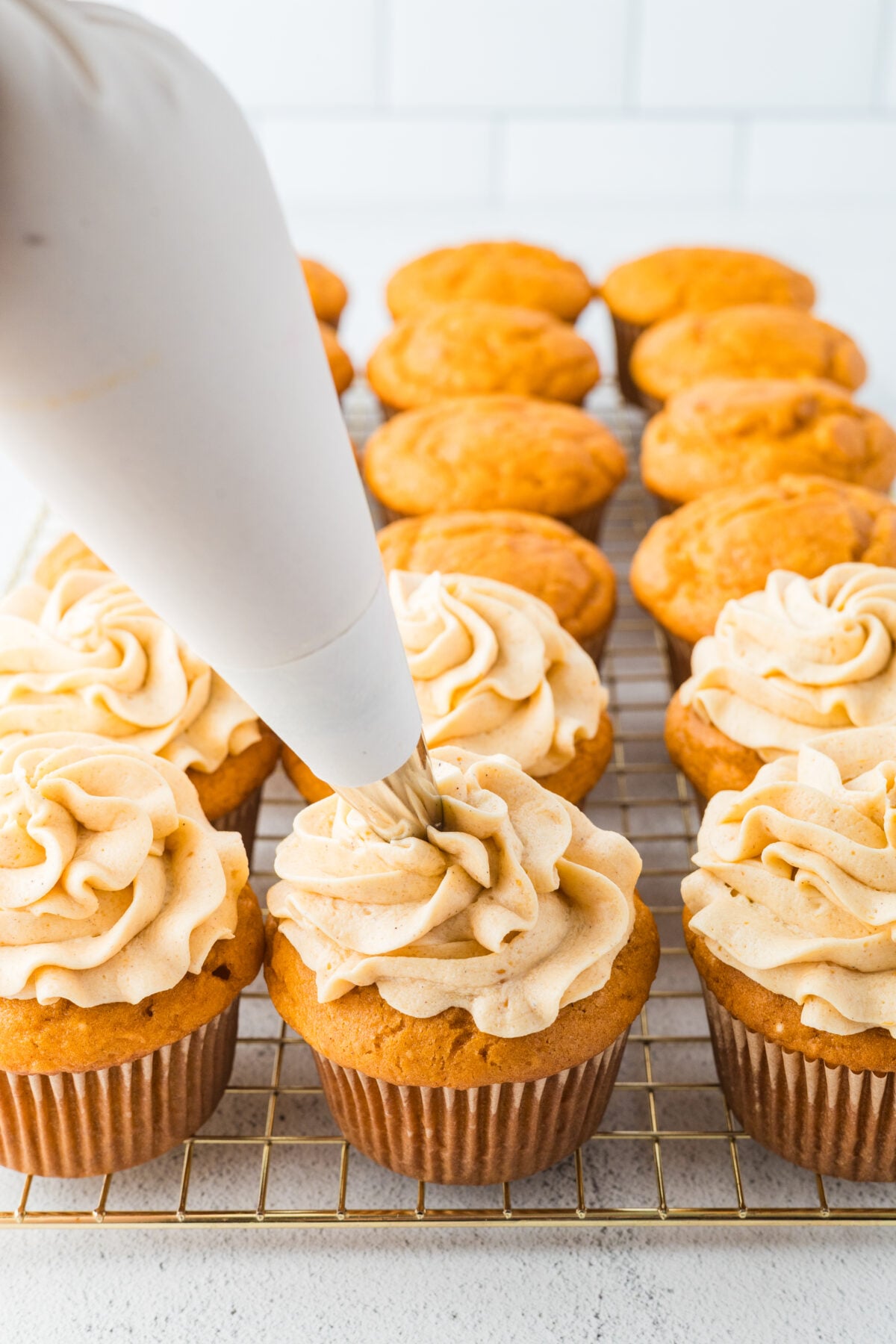 piping frosting onto cupcakes