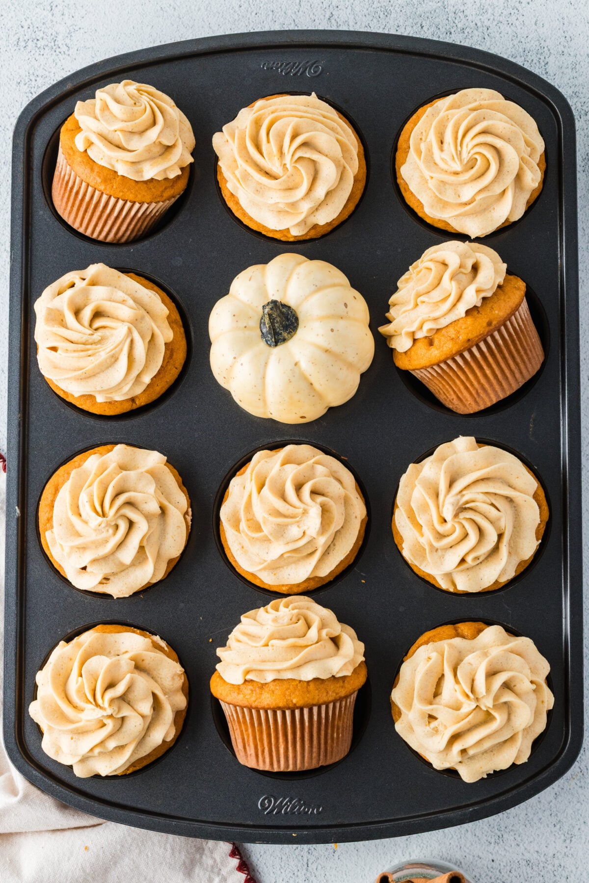 frosted pumpkin spice cupcakes on a muffin pan