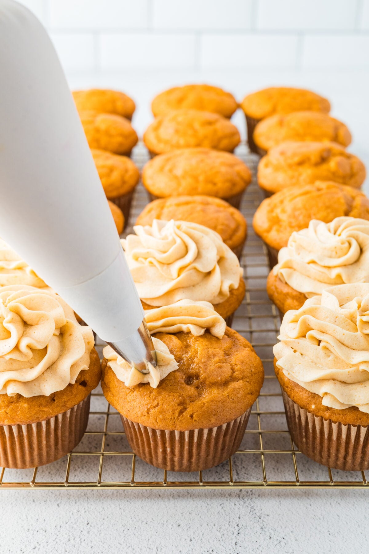 piping frosting onto cupcakes