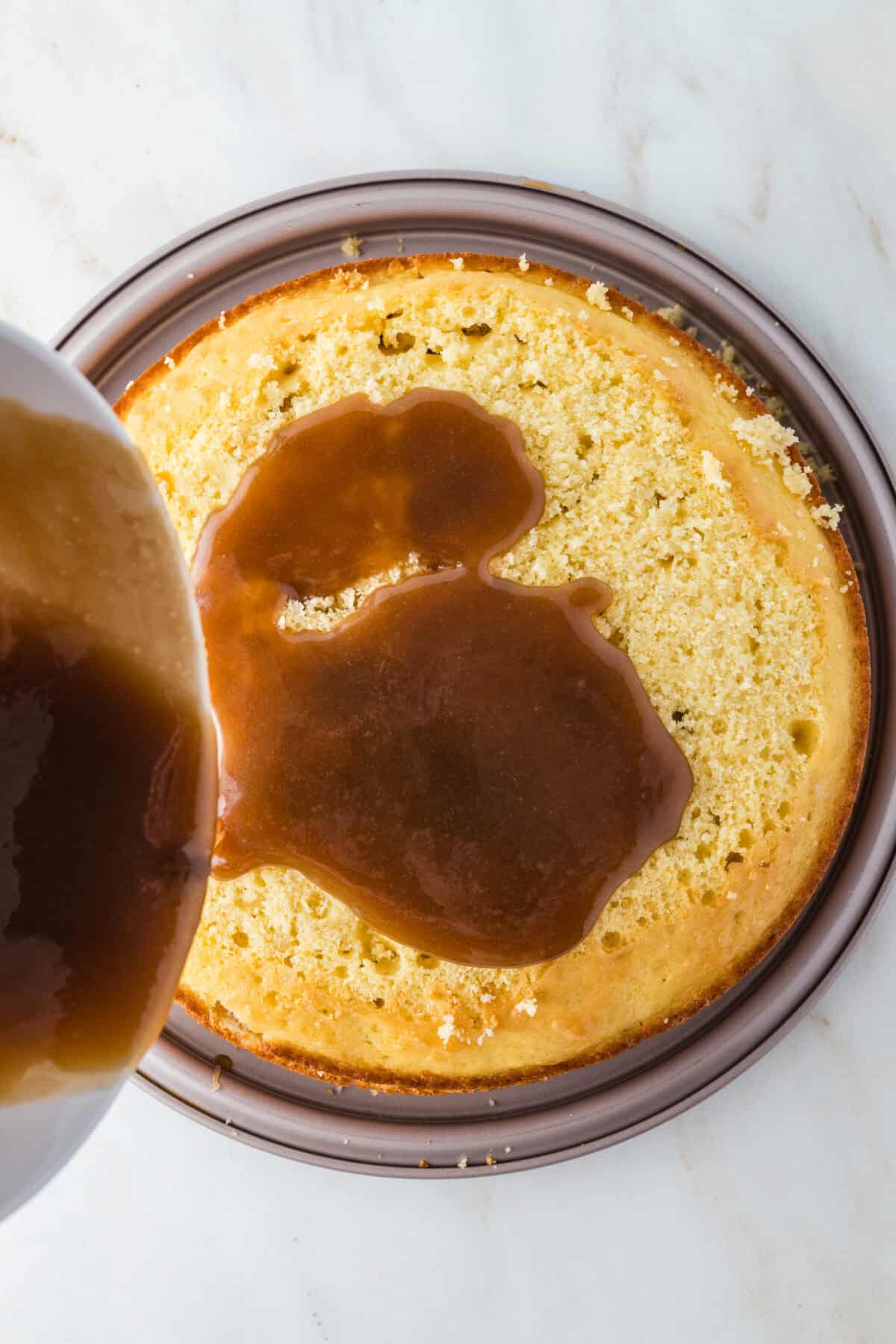 caramel filling being poured on torted cake