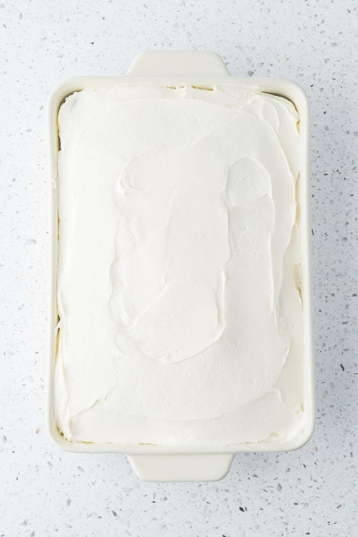 cream cheese frosting spread on baked carrot cake