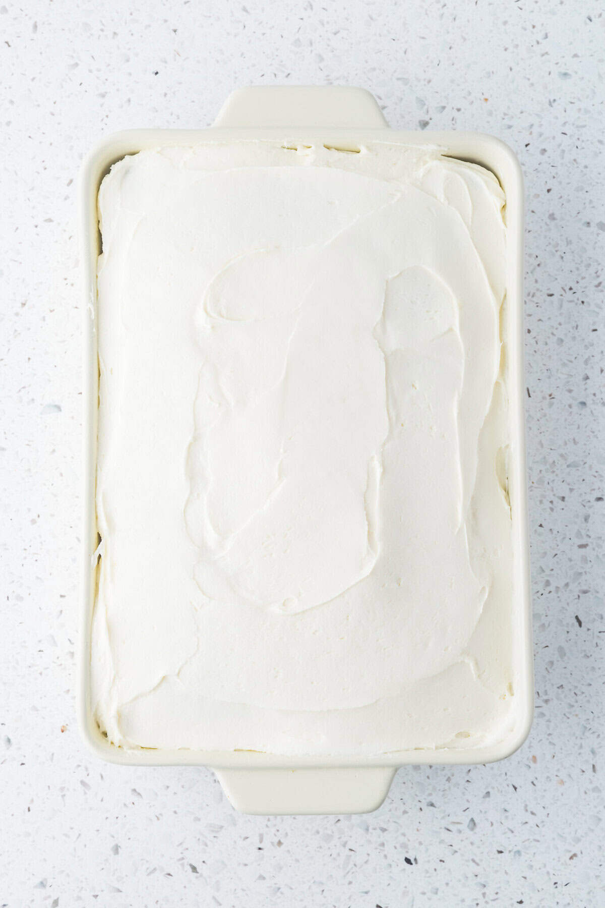 cream cheese frosting spread on baked carrot cake