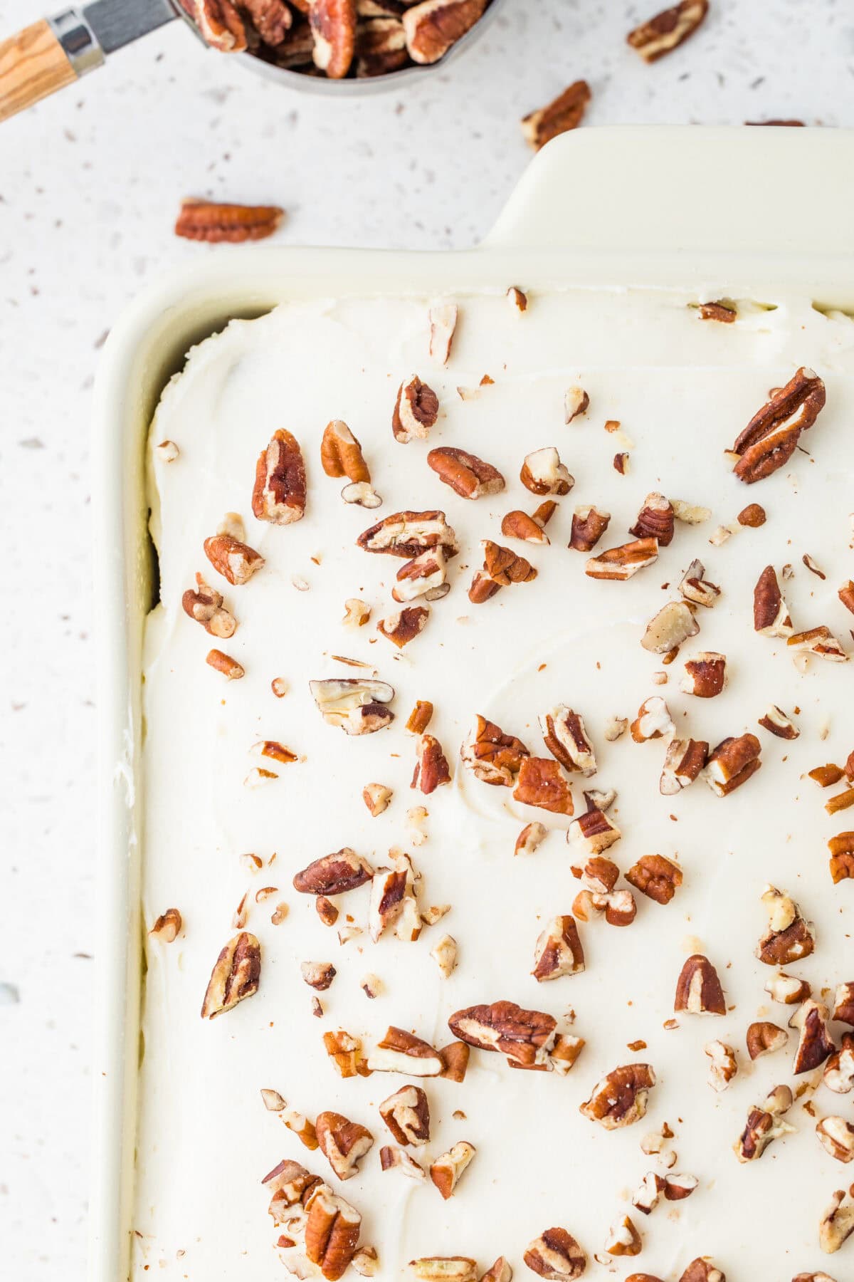 carrot cake with cream cheese frosting and pecans on top