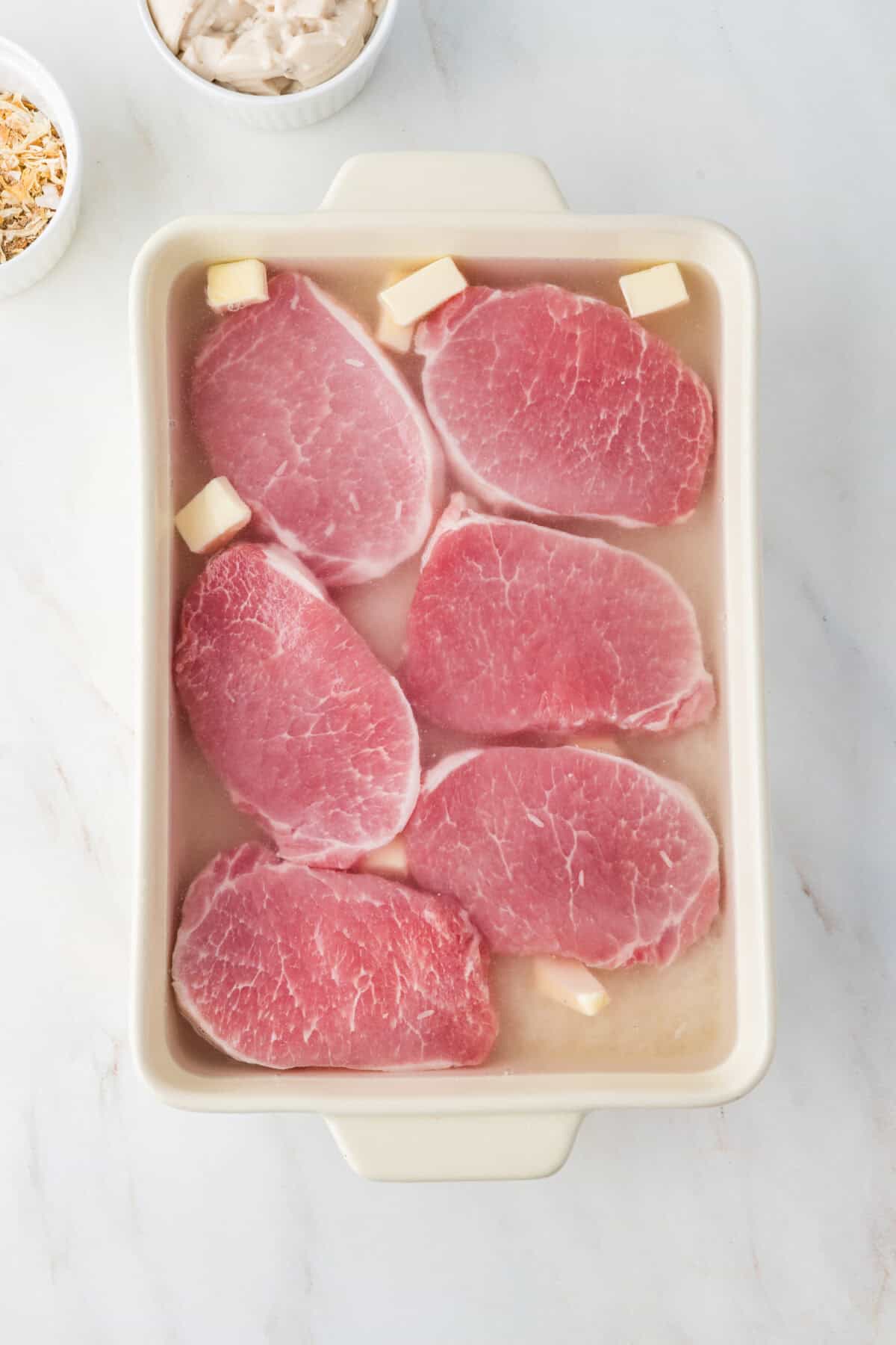 pork chops on top of the rice in the baking dish