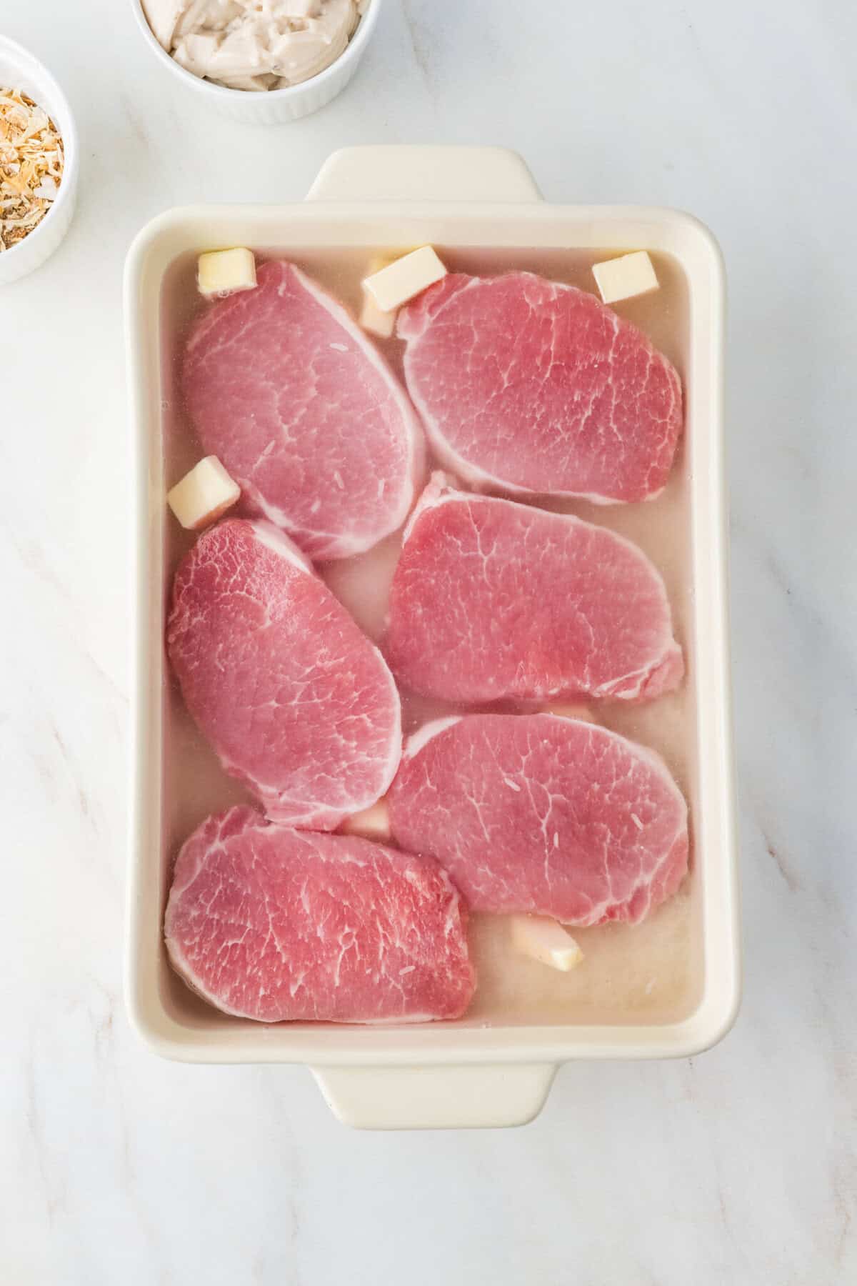 pork chops on top of the rice in the baking dish