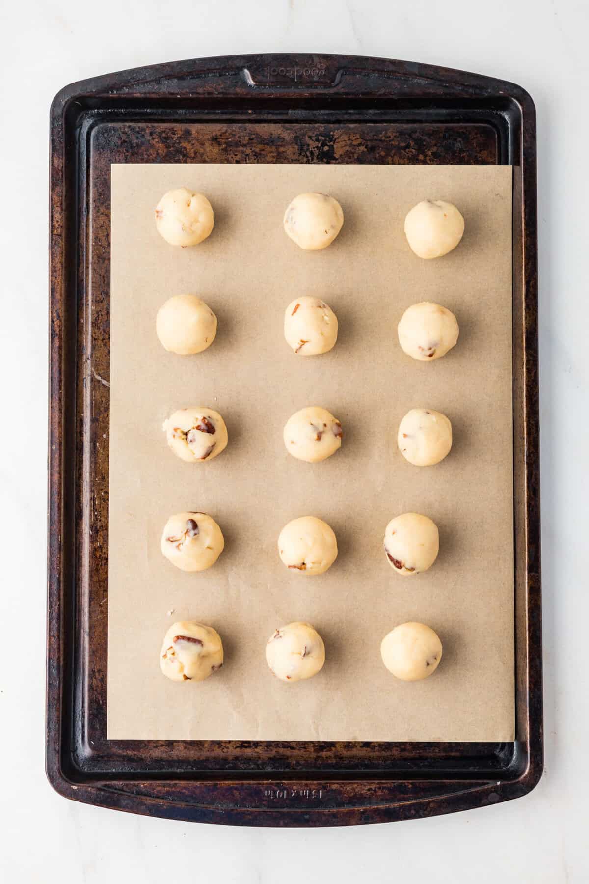 mexican wedding cookies on parchment on a baking sheet