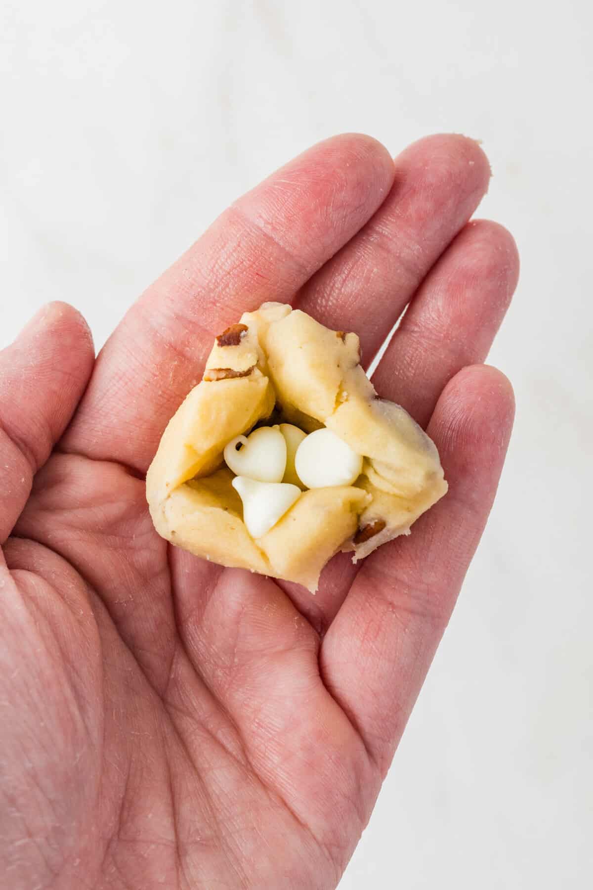 adding white chocolate chips into middle of cookie