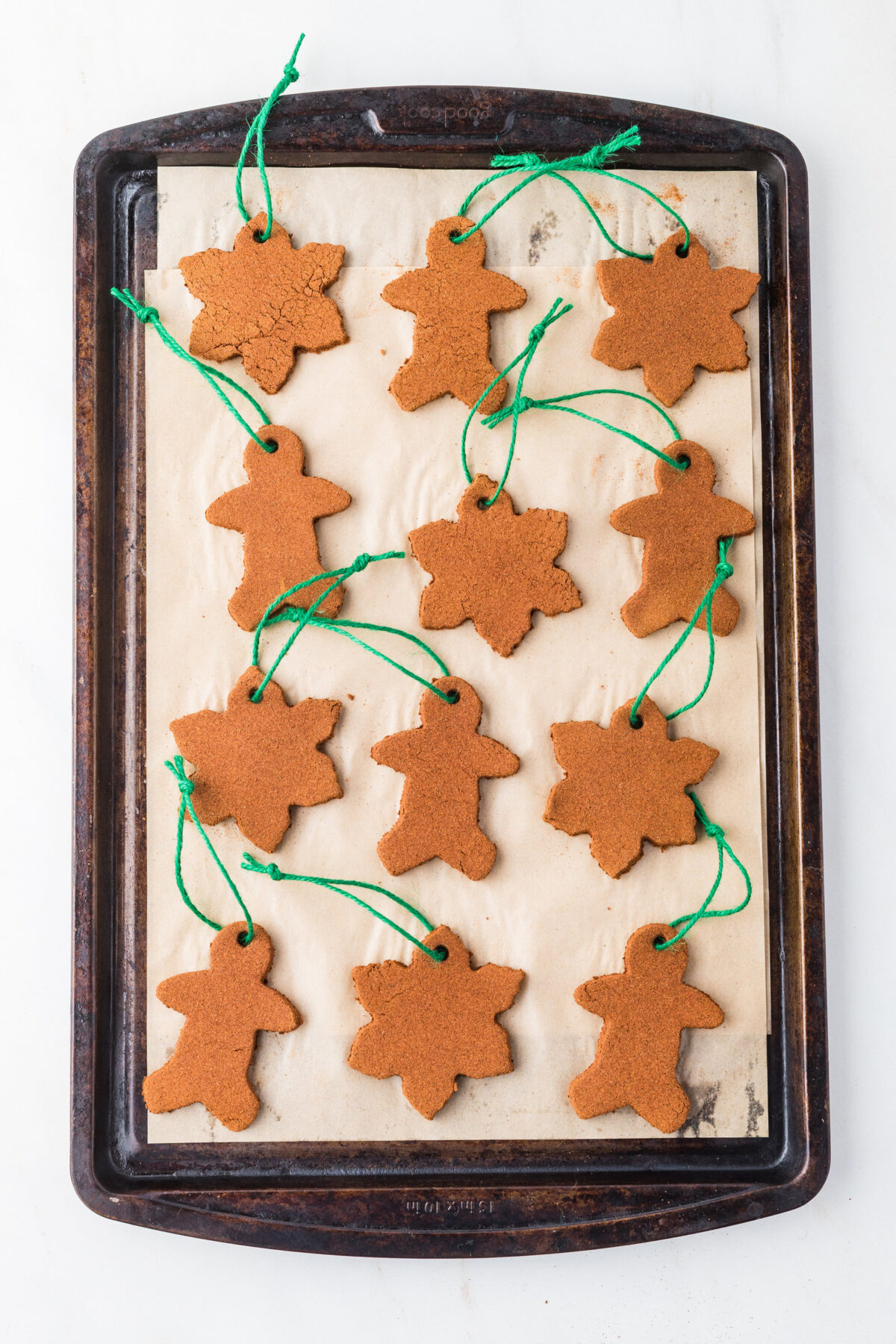 ornaments on a sheet pan with green twine threaded through the holes