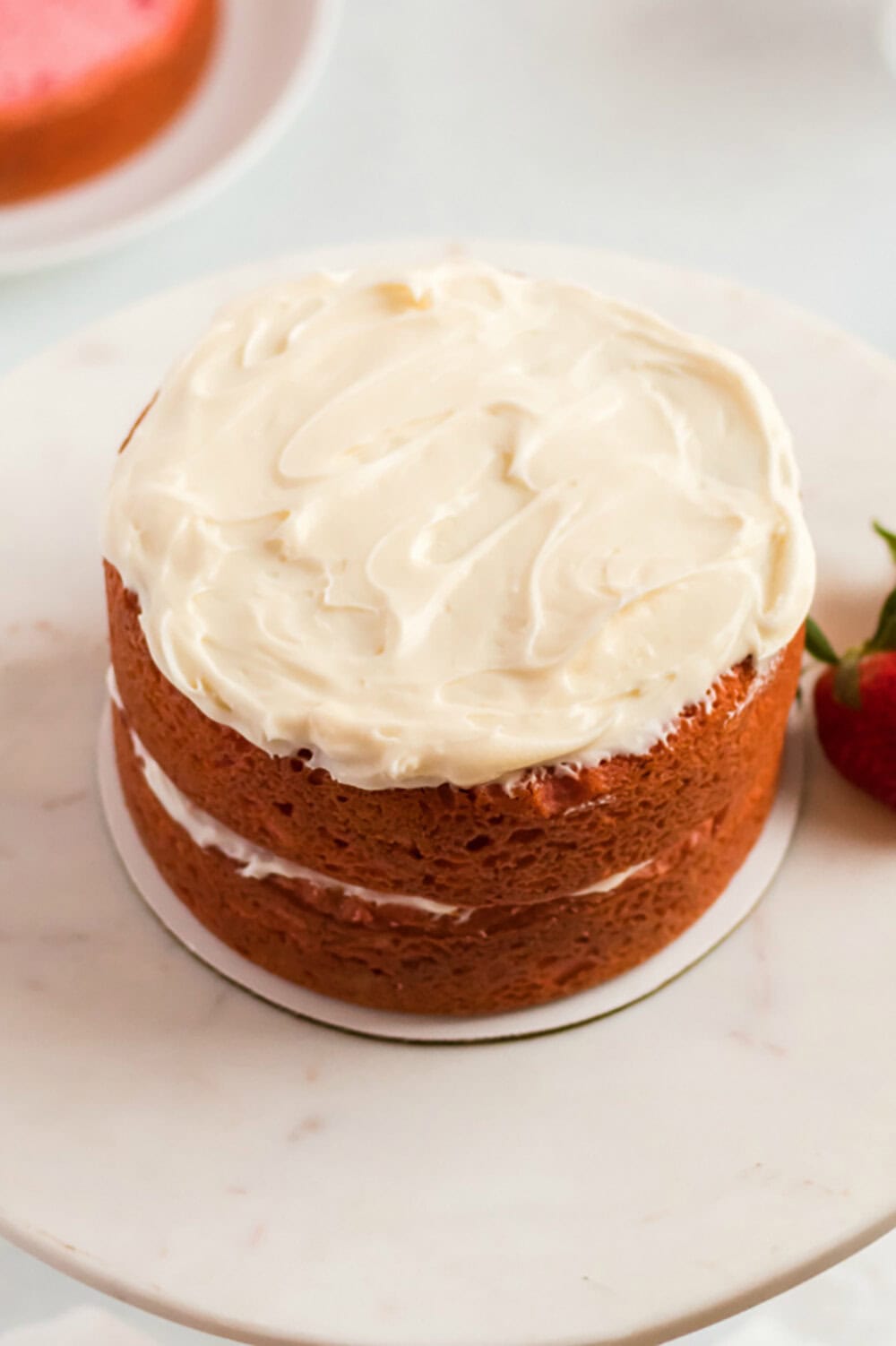 two layers of strawberry cake with cream cheese frosting between 