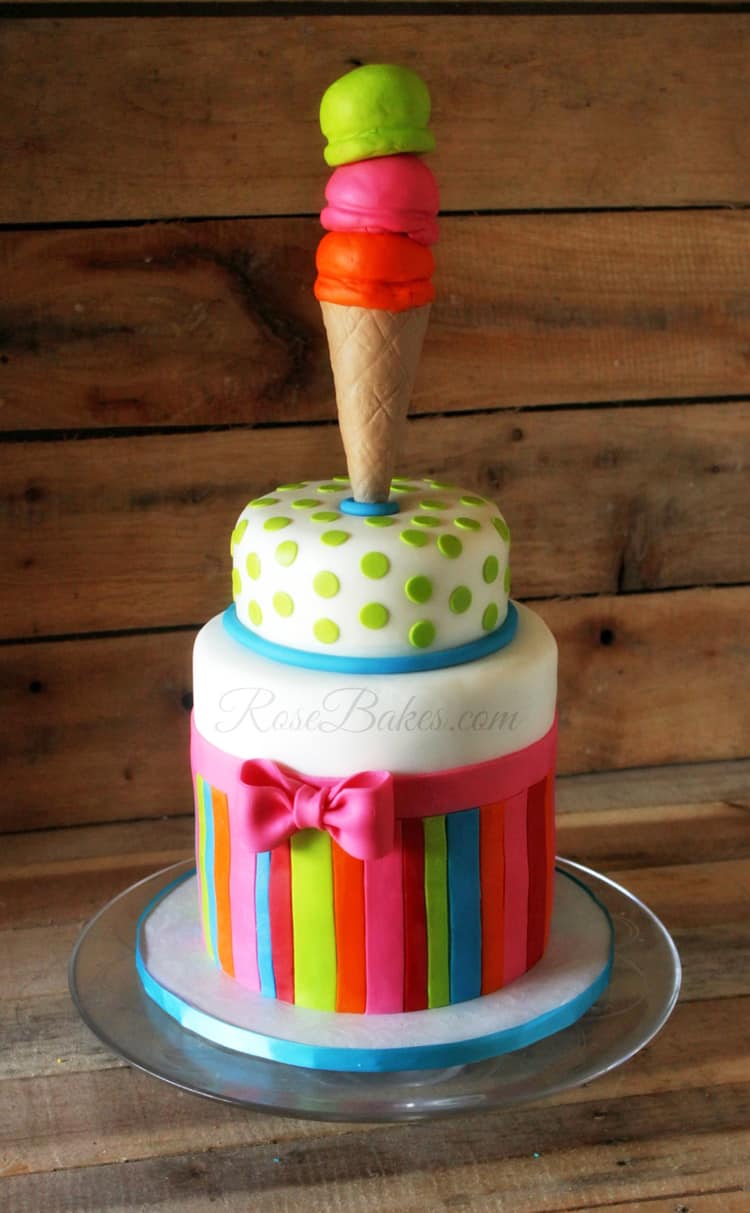 Icecream cone standing on top of 2 tiered polka dots and stripes cake