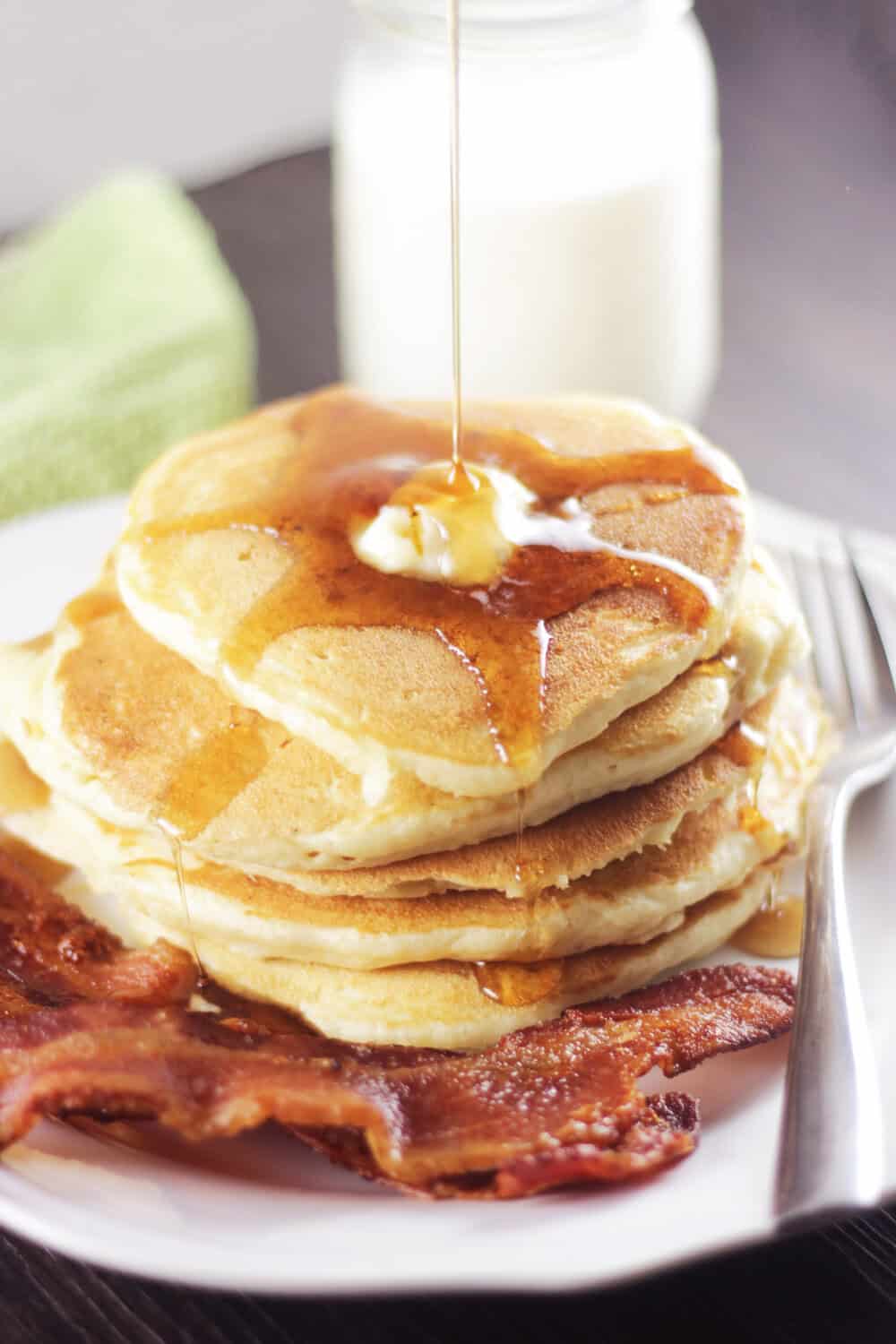 fluffy buttermilk pancakes with syrup being drizzled over the top