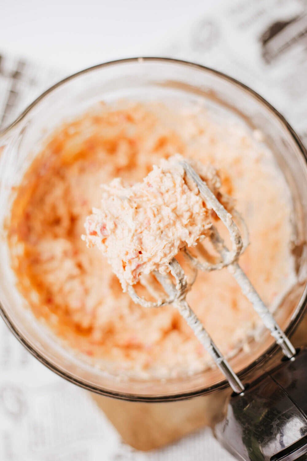 mixer blades over a bowl of pimento cheese after mixing the pimento spread