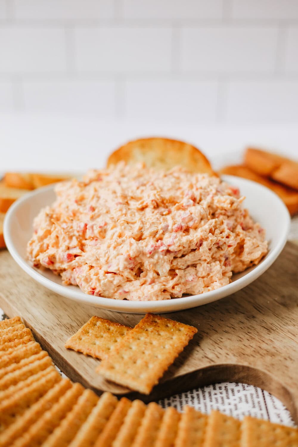 homemade pimento cheese spread in a white bowl surrounded by crackers