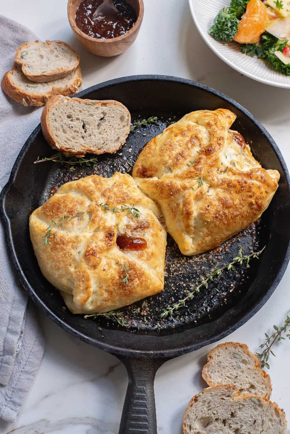 baked brie in puff pastry with thyme and sugar and crispy bread in a skillet