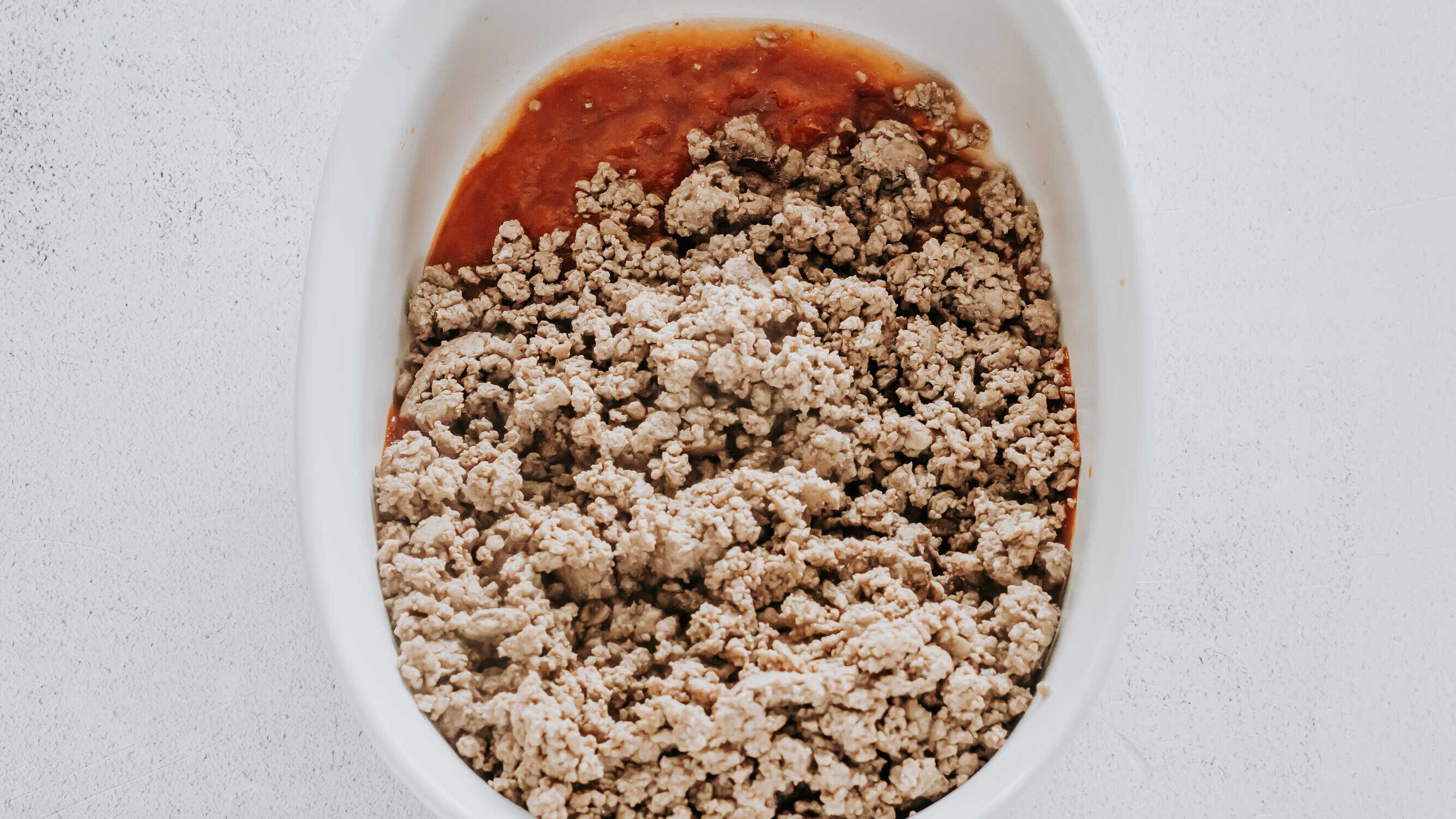 cooked ground beef over pizza sauce
