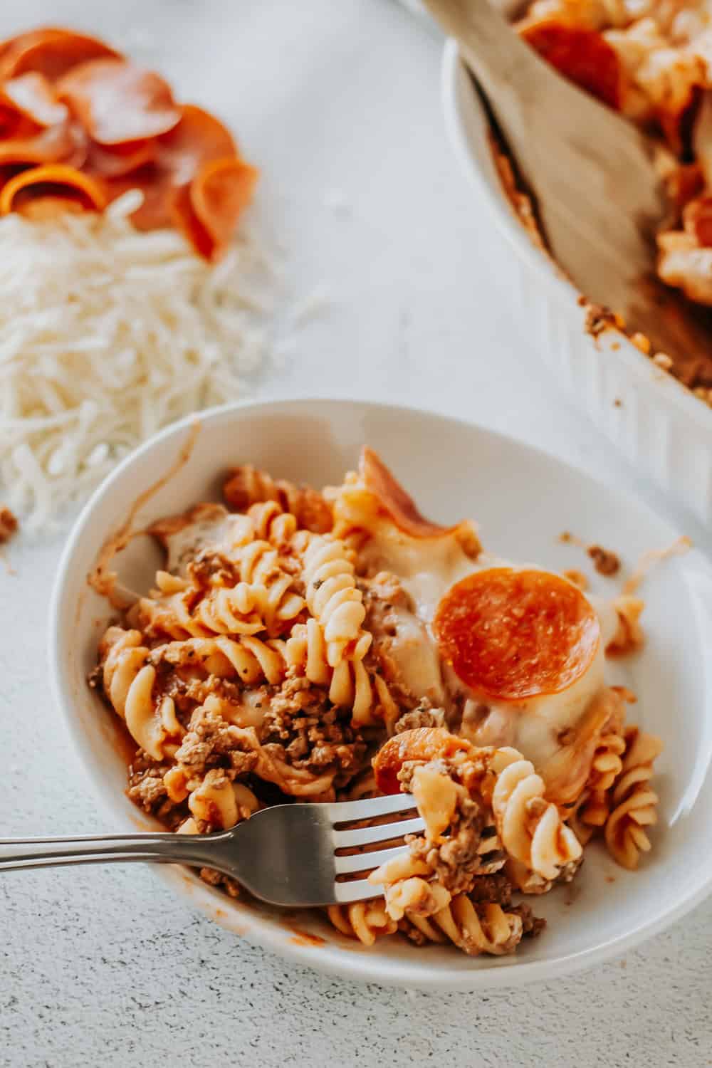 a bowl of pepperoni pizza casserole with a fork