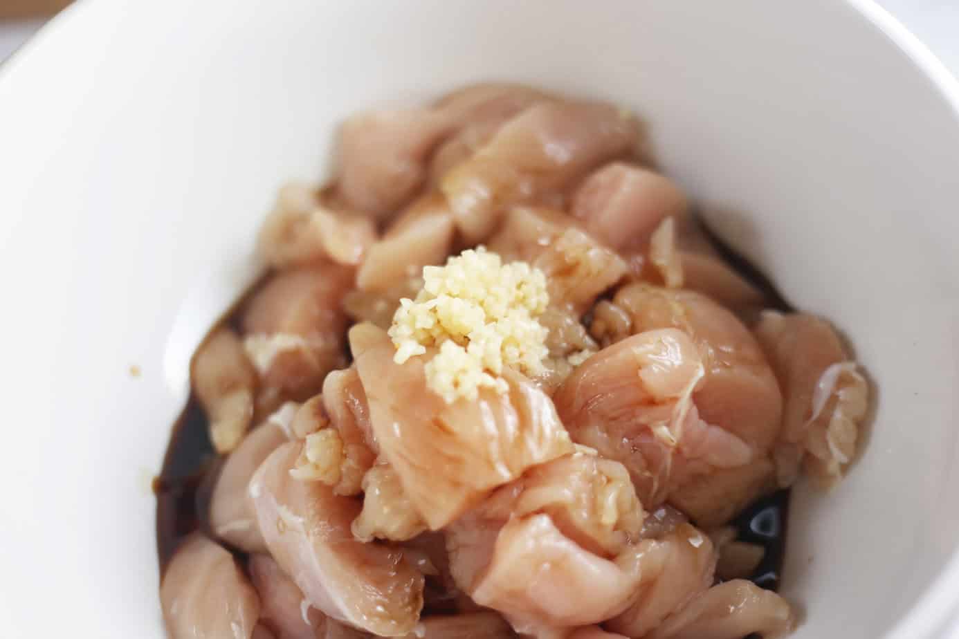 chicken chunks in a white bowl with garlic and soy sauce