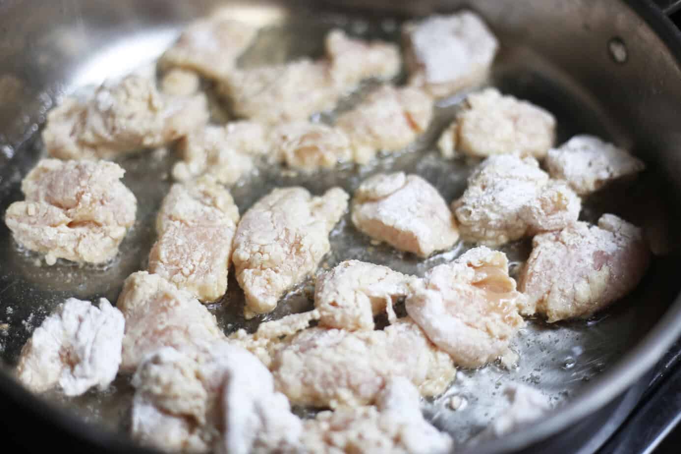 battered chunks of chicken in a skillet