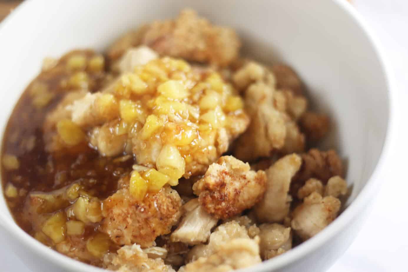 orange pineapple sauce poured over chicken in a bowl