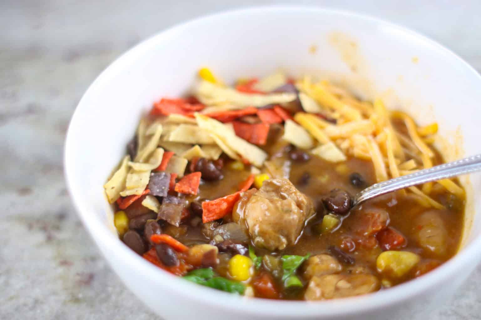 Instant Pot Chicken Tortilla Soup in white bowl with cheese, cilantro and tortilla strips