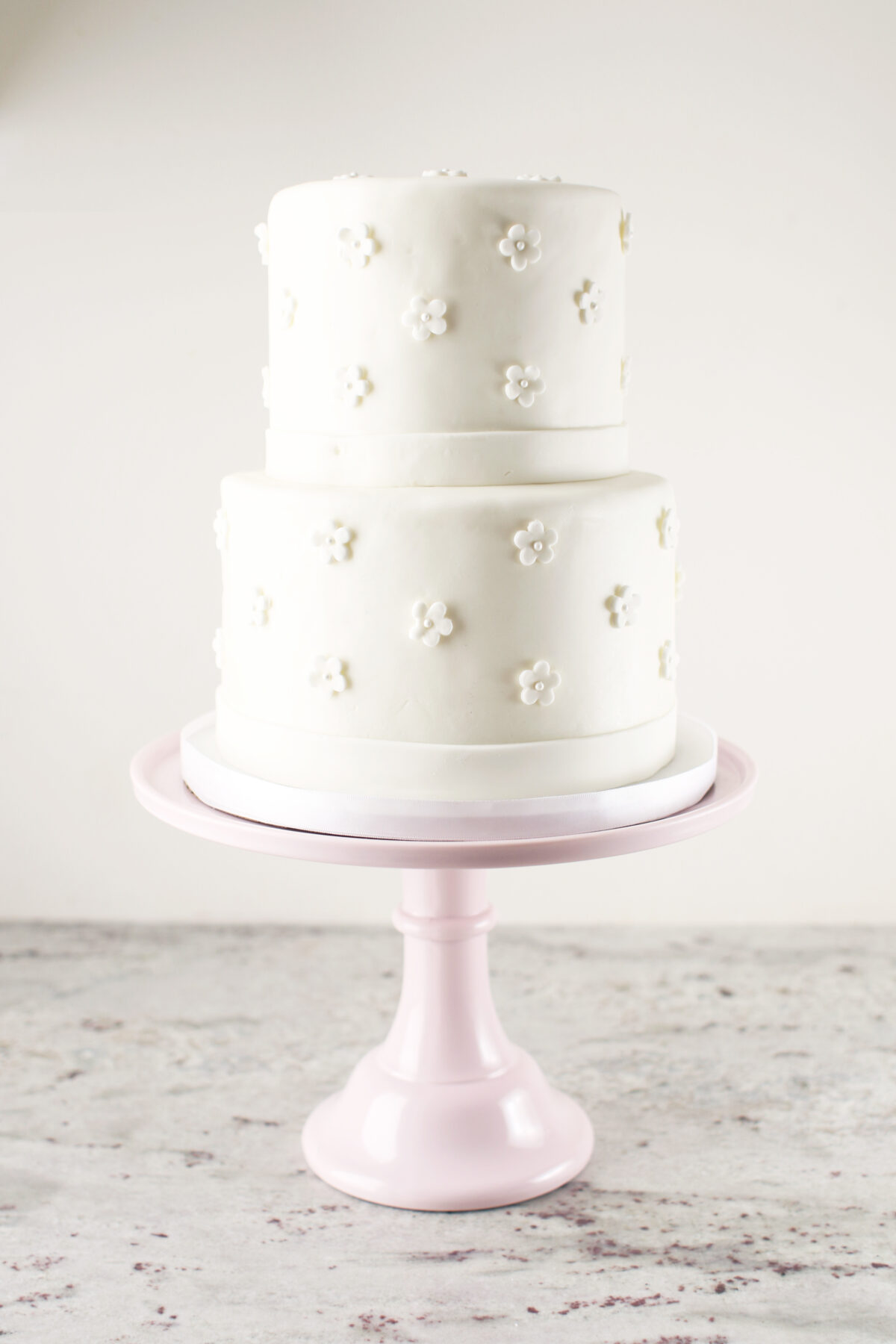 fondant wedding cake with flowers on a pink stand