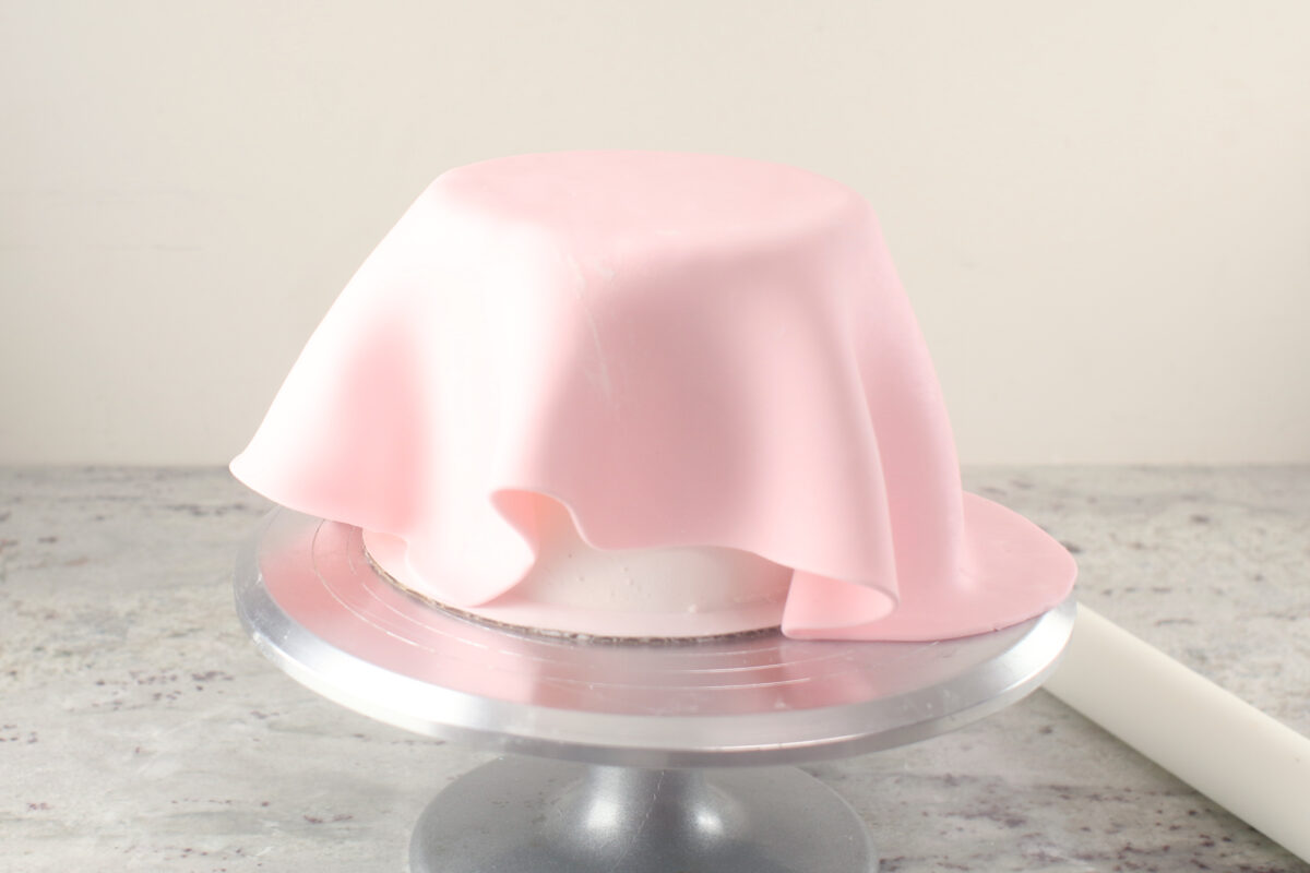 rolled marshmallow fondant over a cake on a turntable