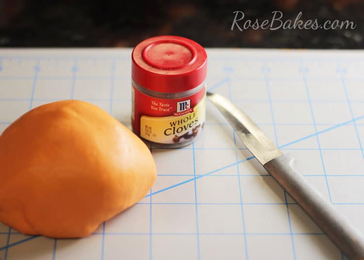 orange fondant whole cloves and sculpting tool laid out for use