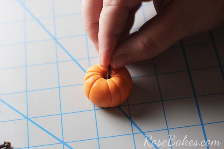 brown stem being placed on pumpkin topper