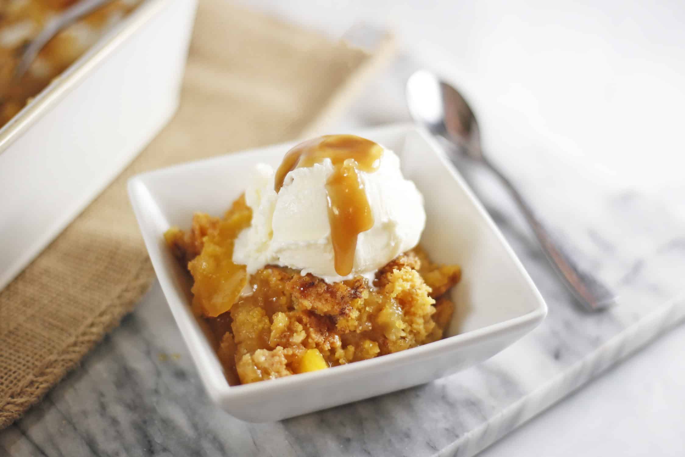 peach dump cake with vanilla ice cream and caramel sauce