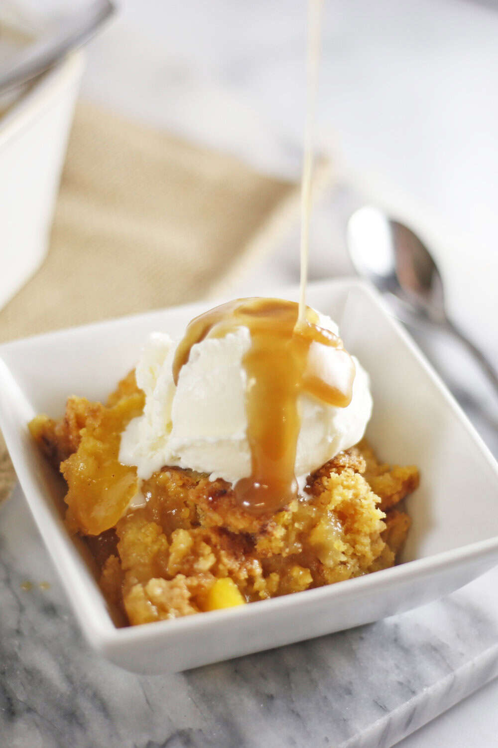 peach dump cake with vanilla ice cream and caramel sauce