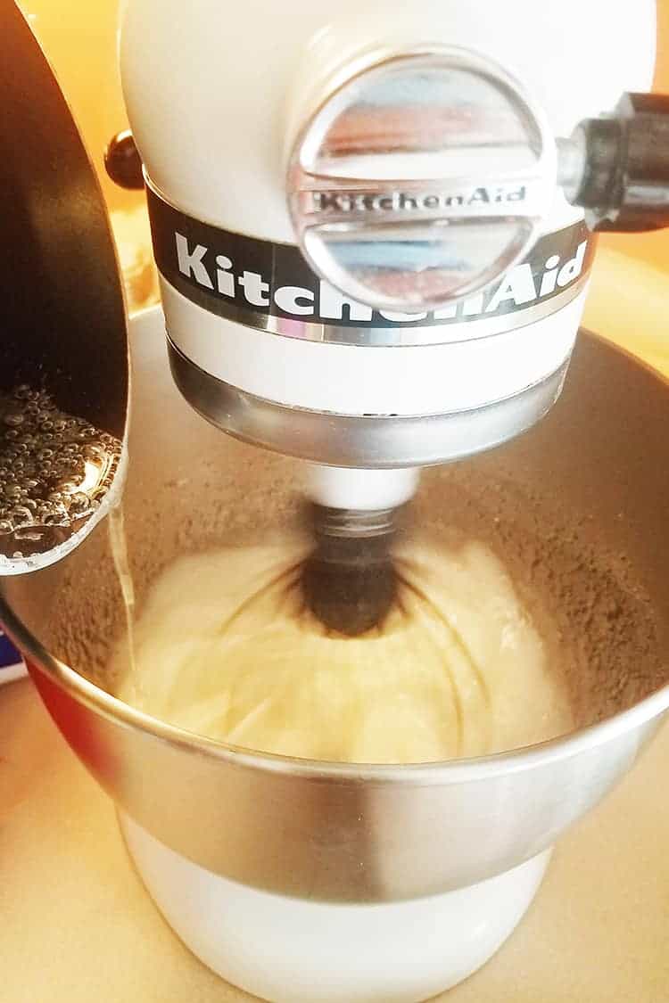 pouring sugar into meringue for strawberry cheesecake macarons