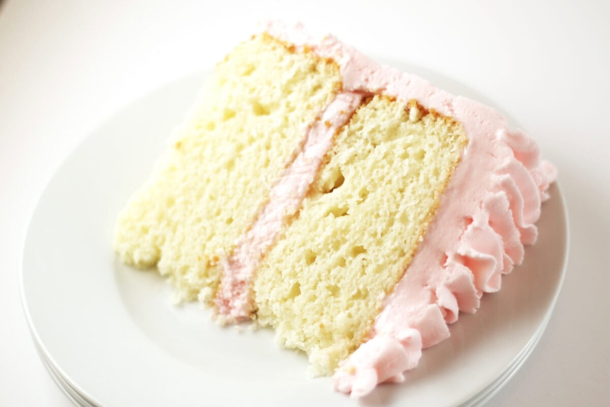 slice of white almond sour cream cake on a white plate