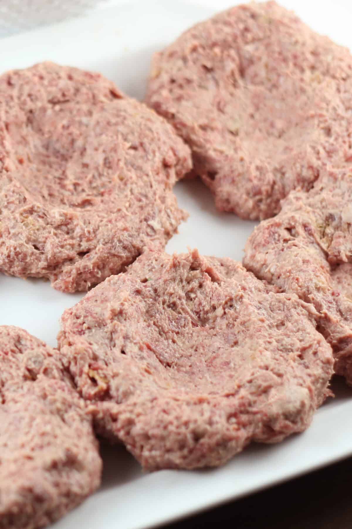 raw burgers on a platter