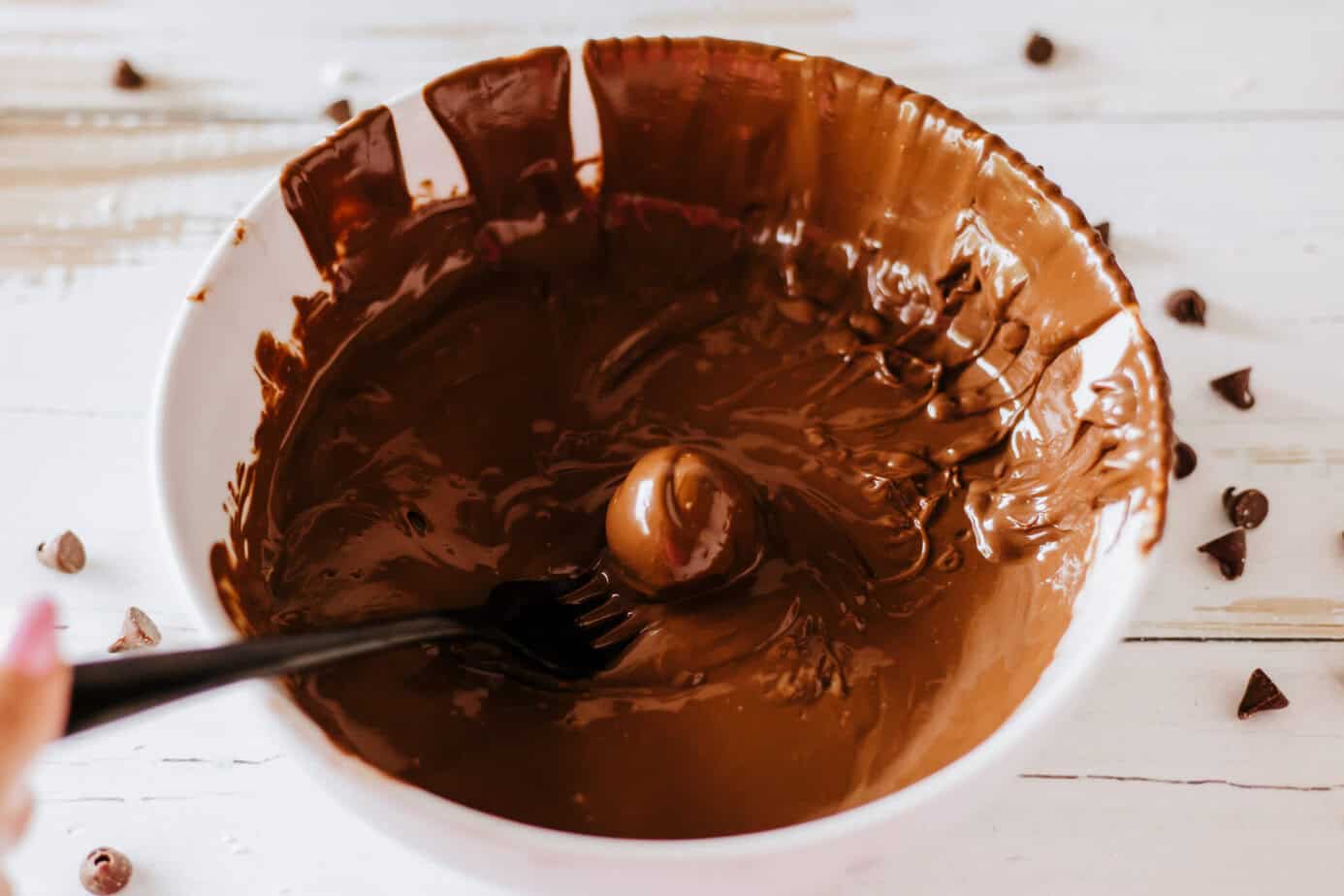 melted chocolate in a bowl with a cherry dipped in it