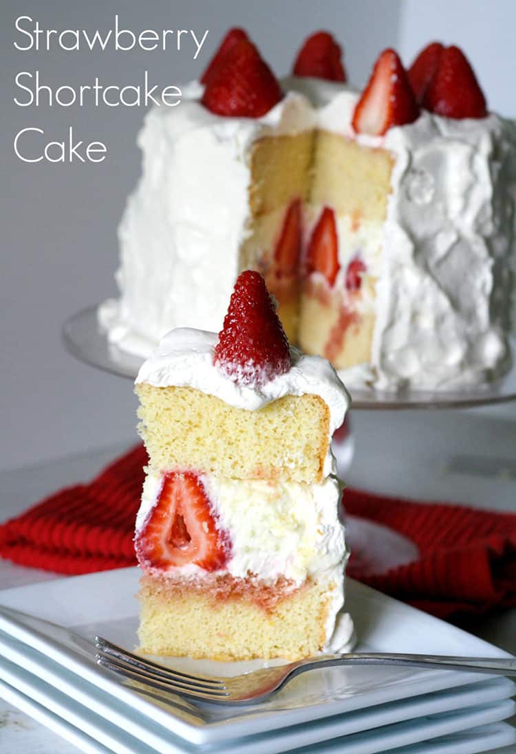 slice of Strawberry Shortcake Cake on white plate with fresh strawberries