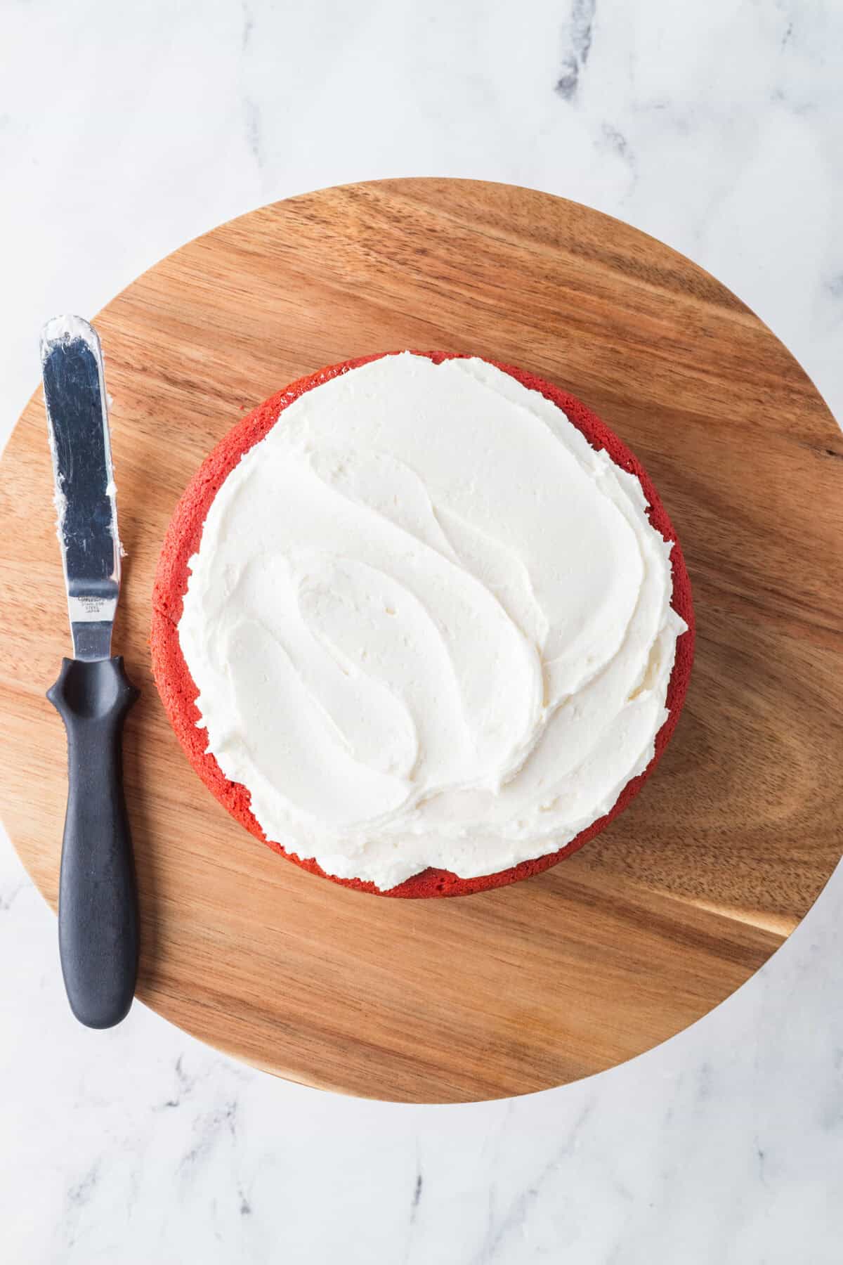 layer of red velvet cake with cream cheese frosting on top