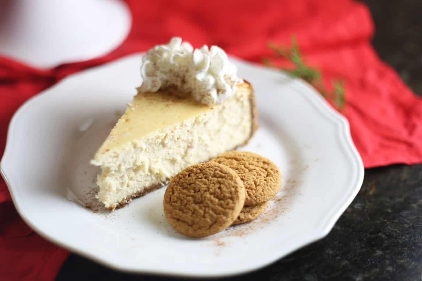 slice of eggnog cheesecake with gingersnap crust on white plate