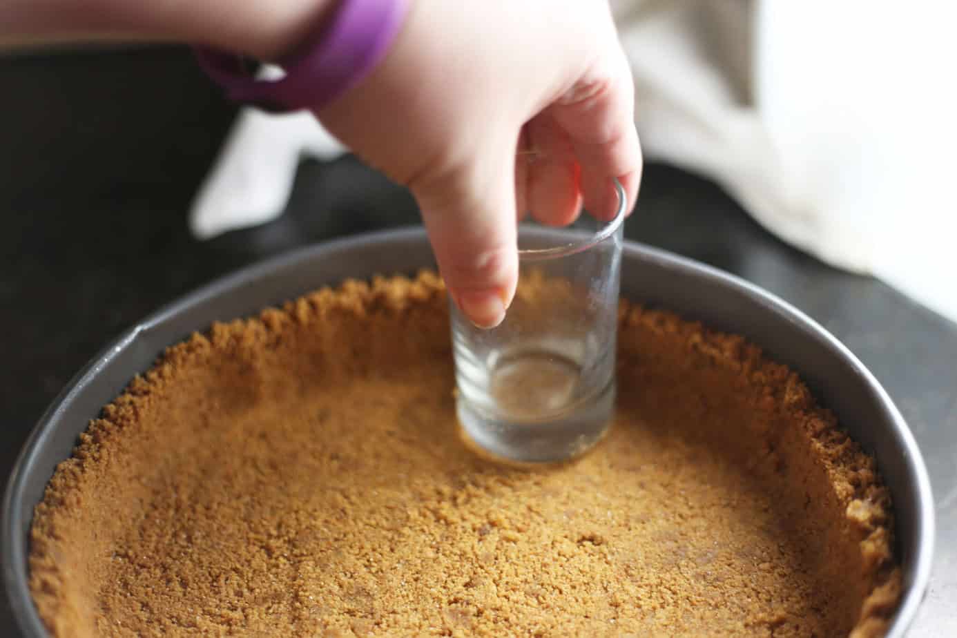using glass to press gingersnap crust in springform pan