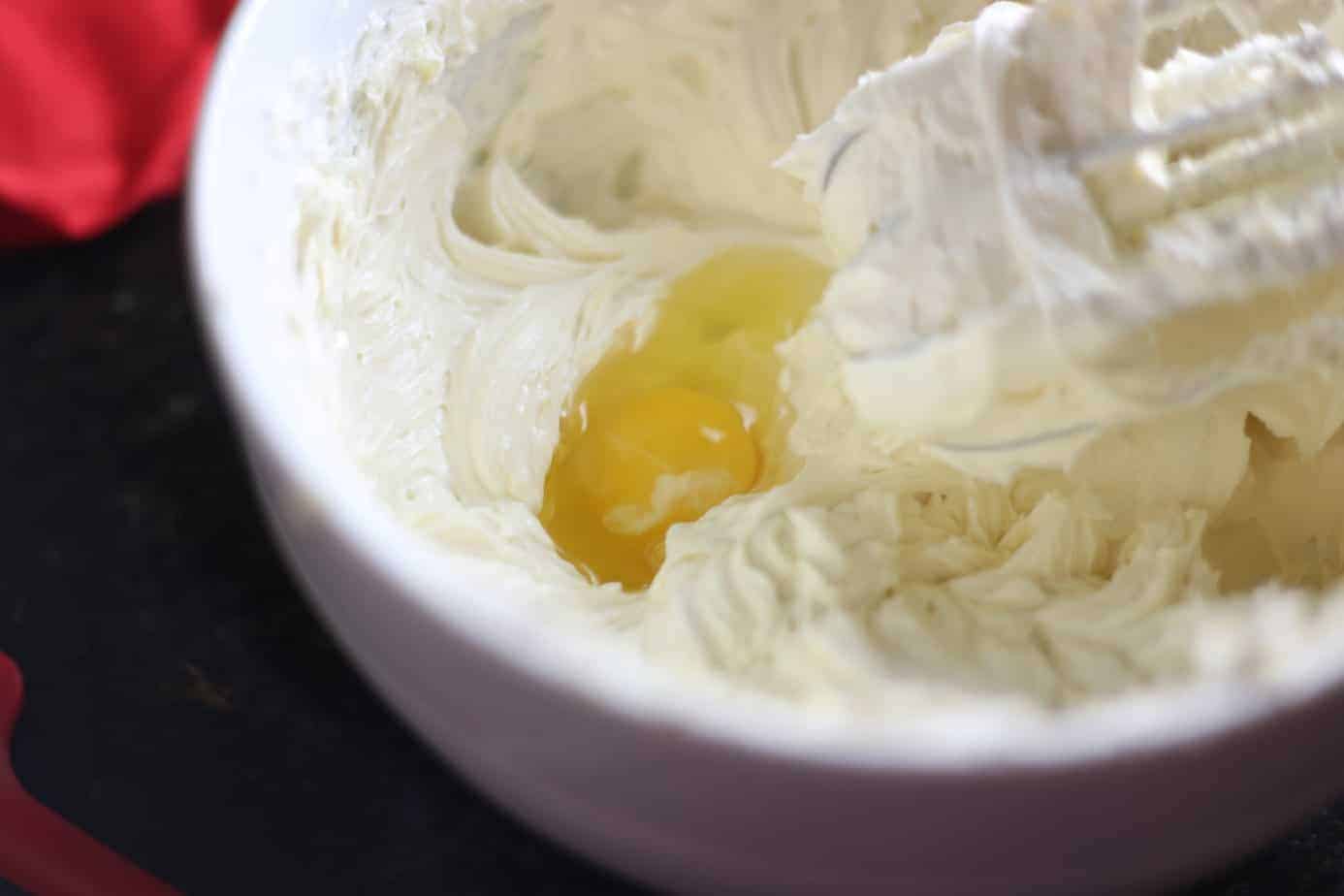 eggs added to whipped cream cheese in white bowl