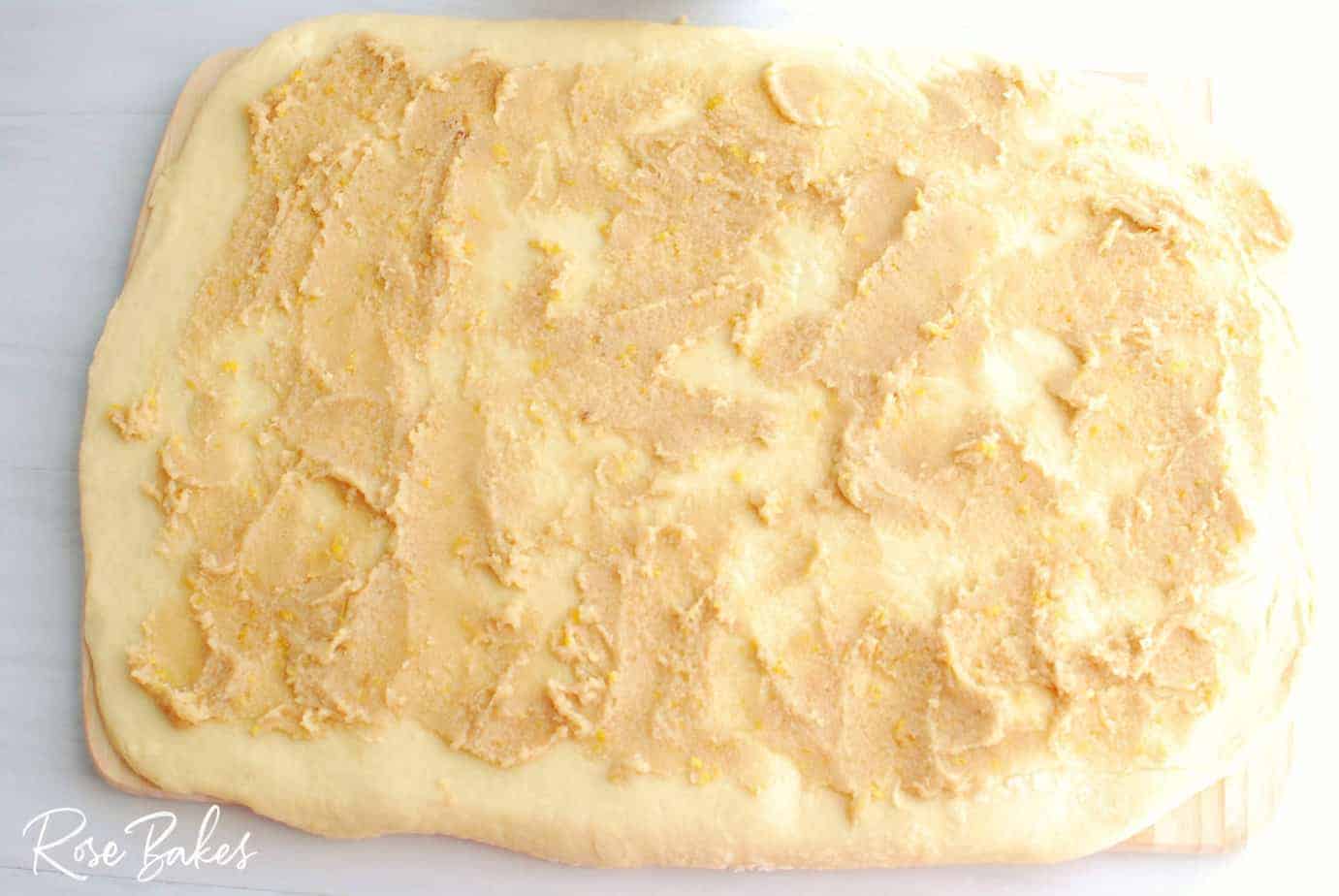 Raspberry Cinnamon Rolls dough rolled out on cutting board with filling spread on top