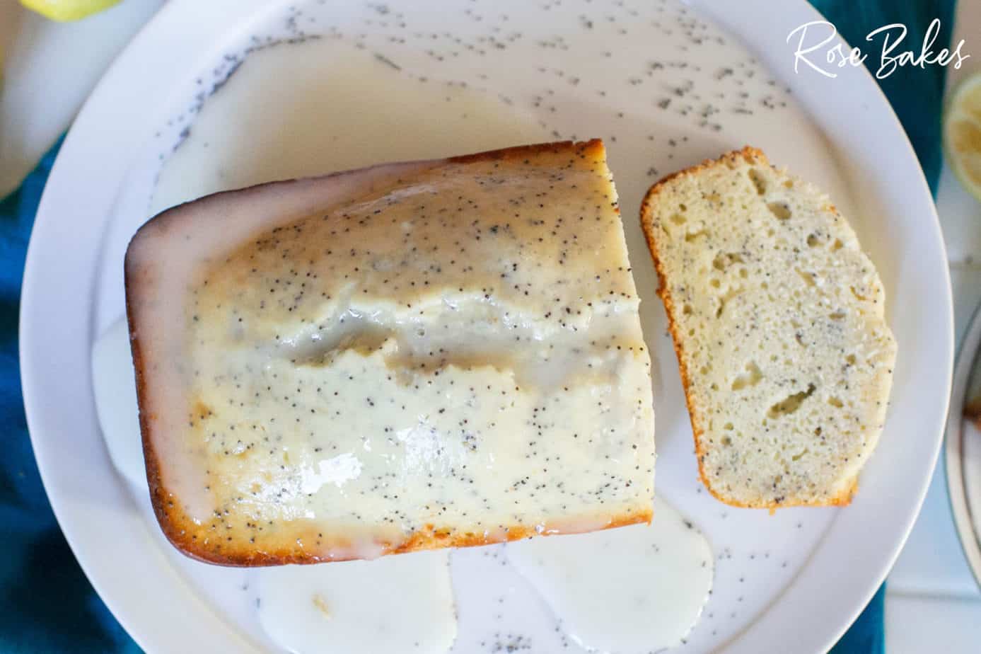 Lemon Poppyseed Loaf sliced on a white cake plate with glaze