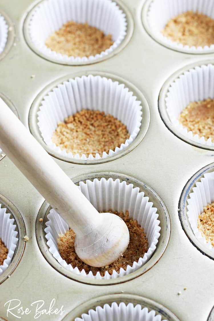 pressing graham cracker crust into cupcake liners in pan