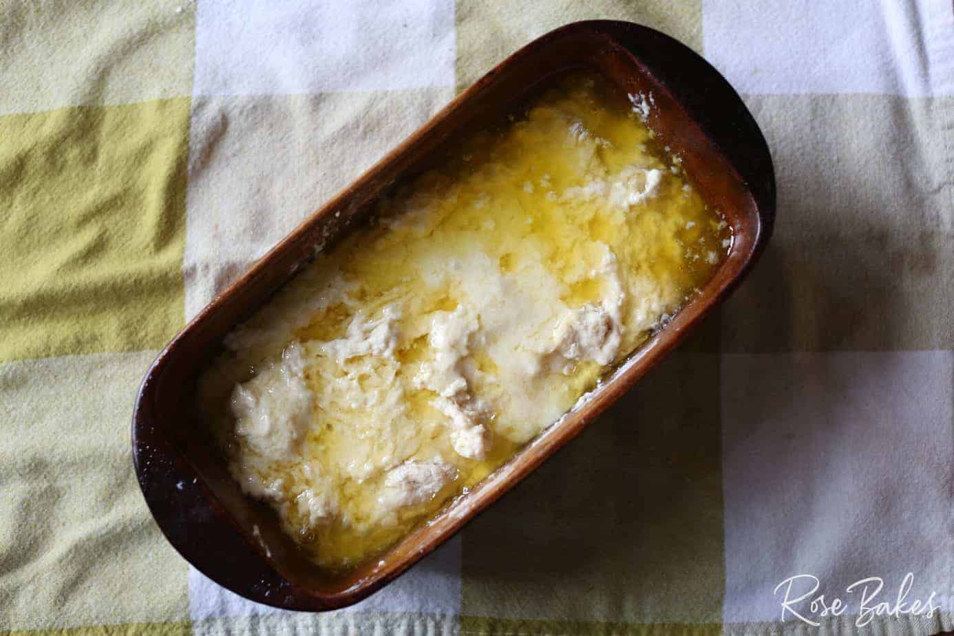melted butter poured over top of dough in baking loaf pan 